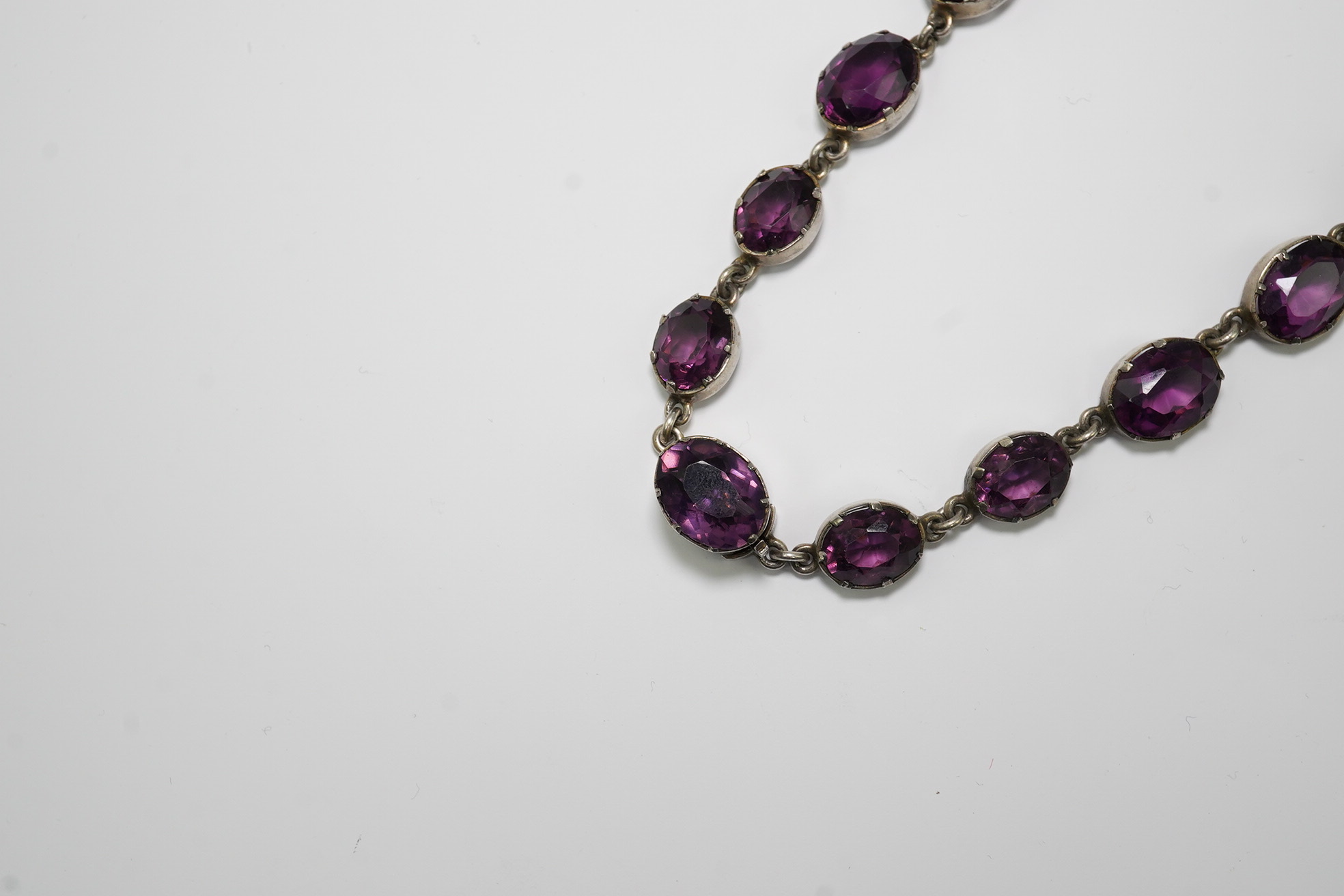 A Victorian silver and graduated oval cut amethyst paste set riviere necklace